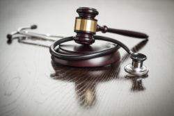 Gavel and Stethoscope on Reflective Wooden Table.
