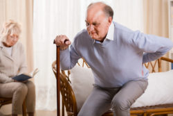 Retired man using walking stick having backache