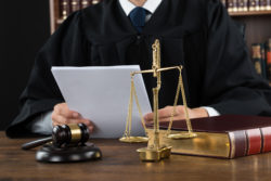 Midsection of judge reading documents at desk in courtroom