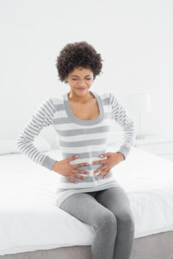 Essure birth control woman on bed holding stomach