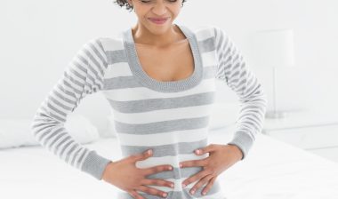 Essure birth control woman on bed holding stomach