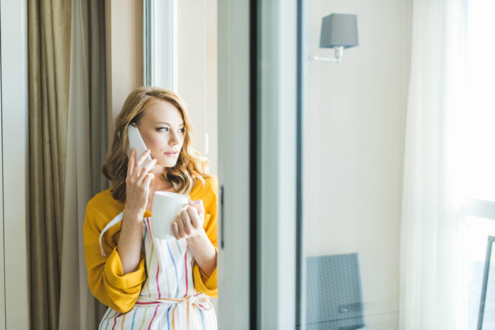 woman on cordless phone looking out her window