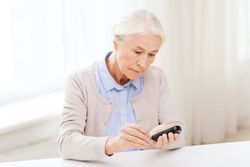 Invokana Invokamet ketoacidosis amputation medicine, age, diabetes, health care and people concept - senior woman with glucometer checking blood sugar level at home