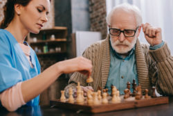 Home care worker playing chess as part of senior in home care services