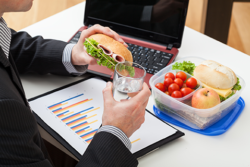 man eating sandwich while working