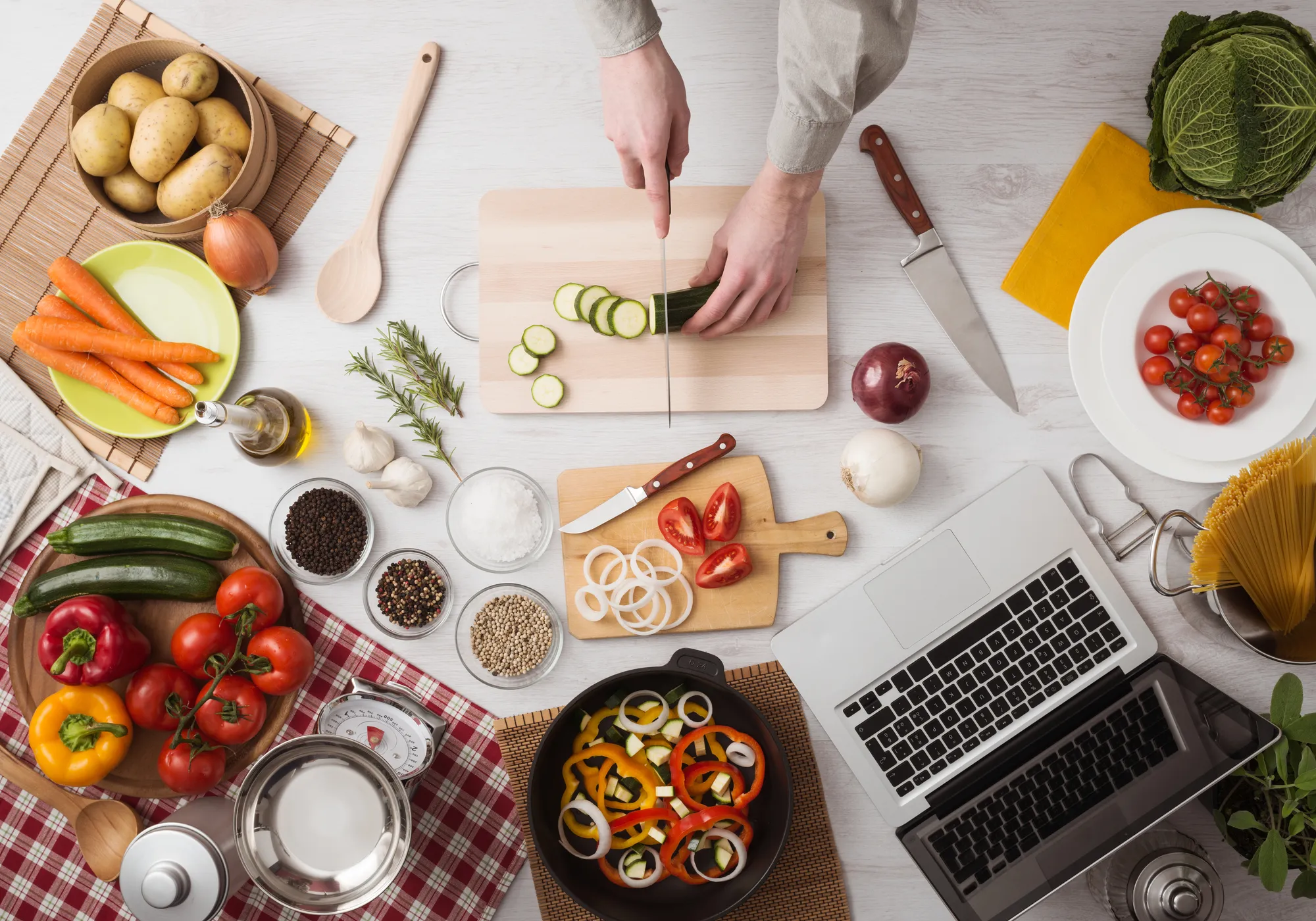 Man cooking in the kitchen and slicing vegetables on a chopping board, top view - marketing calls