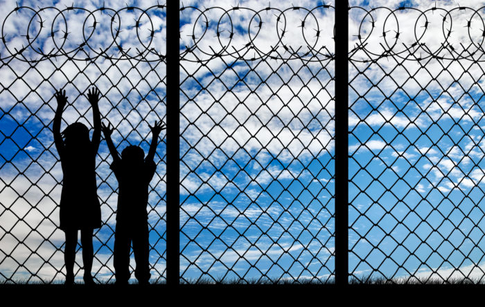 children by fence hoping to be accepted in the U.S.