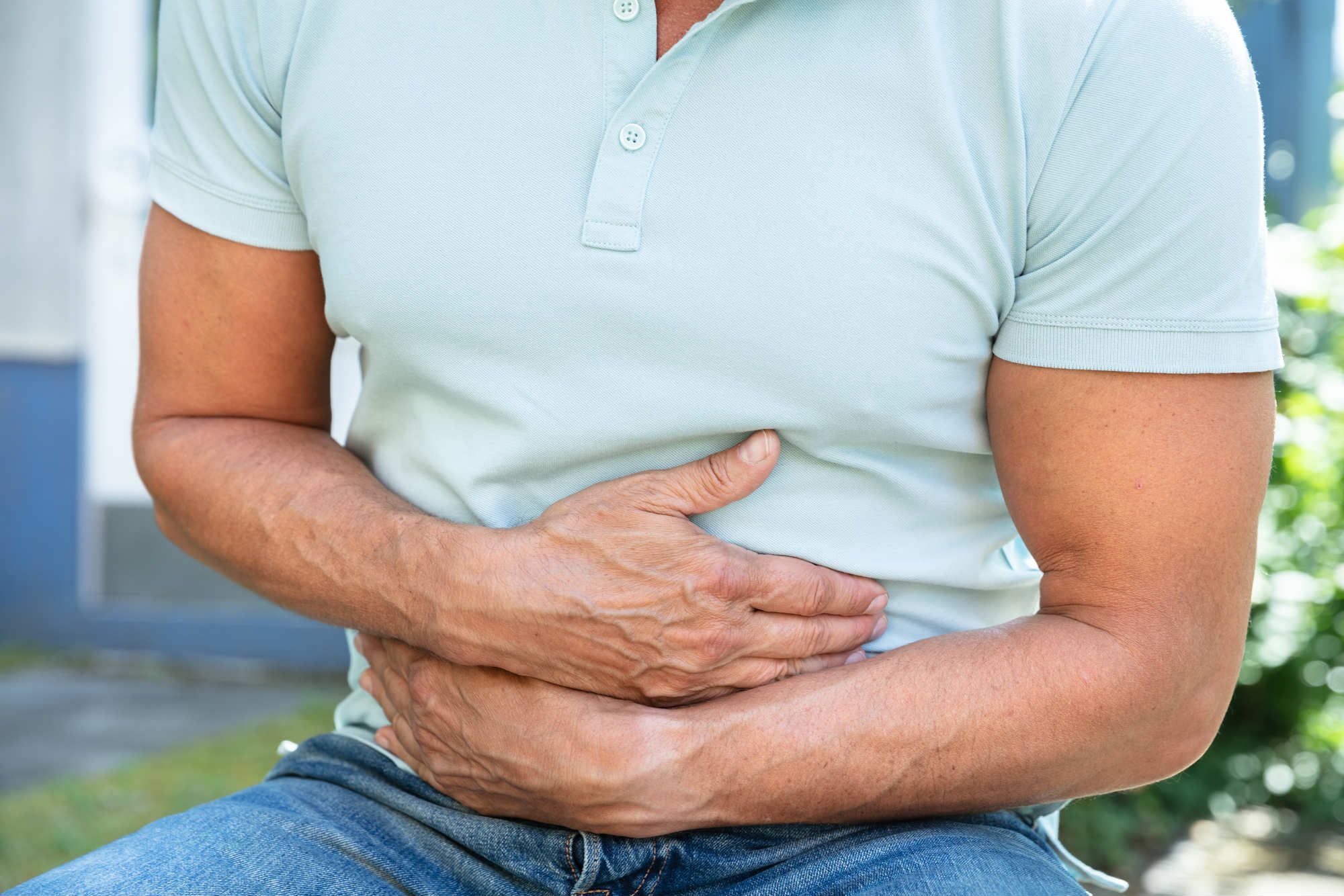 A man in a light-green polo shirt grabs his stomach in pain - la carreta