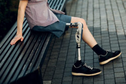 A young man with a prosthetic leg sits on a bench.