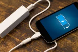 A smartphone is being charged with a portable charger.