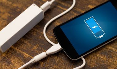 A smartphone is being charged with a portable charger.