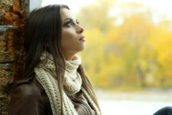 Concerned woman sitting by a wall