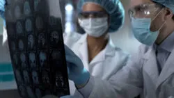 Two doctors examine a CT scan of a patient's brain.