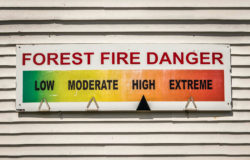 A forest fire danger sign reads high