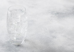 A glass of sparkling water on grey background