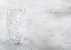 A glass of sparkling water on grey background