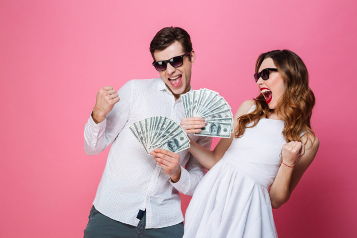 couple happily holding money that they received from settlements