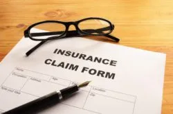 Disability insurance claim form with reading glasses and a pen