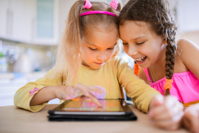 two girls playing games on a tablet through Facebook app