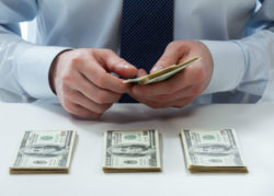 A man is counting hundred dollar bills.