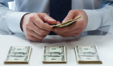A man is counting hundred dollar bills.