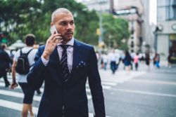 a man in a suit taking a call in a crosswalk