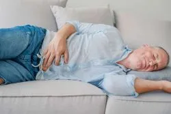 Man lying down in pain due to hernia mesh