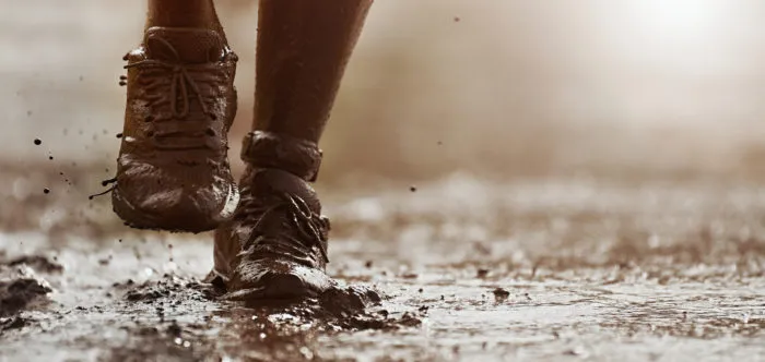 runner's shoes covered in mud competing in Tough Mudder