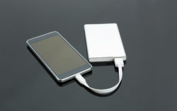 A smartphone is connected to a portable charger.