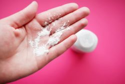 woman holding powder in hand on red background