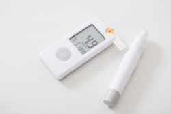 A glucometer and diabetes test on white background.