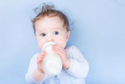 baby drinking formula on blue background