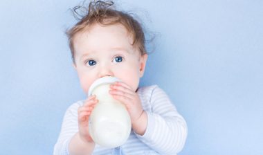 baby drinking formula on blue background