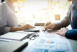 Two bank employees work at a desk.
