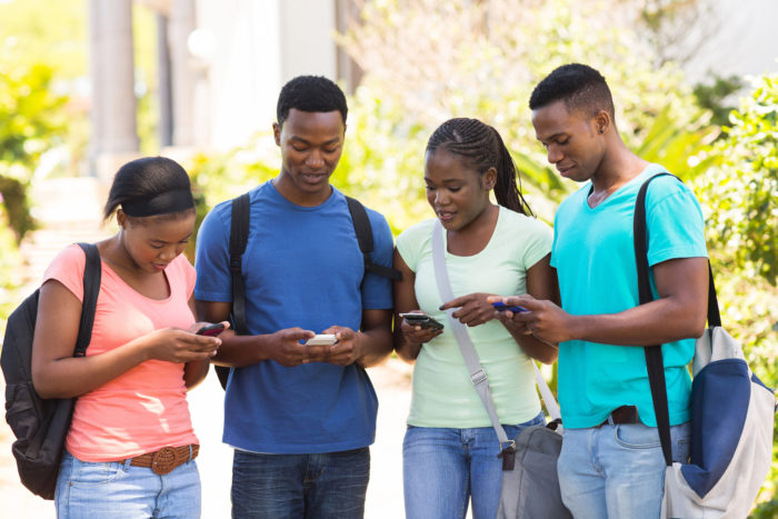 college students standing together using their smartphones