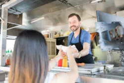 A man serves food at a concession stand.
