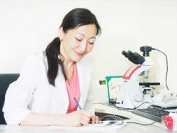 A doctor takes notes at a desk.