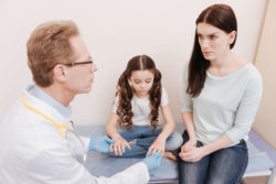 A mother listens to her daughter's doctor.
