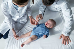 Two doctors are examining a baby.