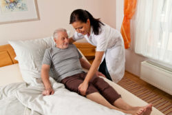Elderly man in nursing home bed receiving care from nurse