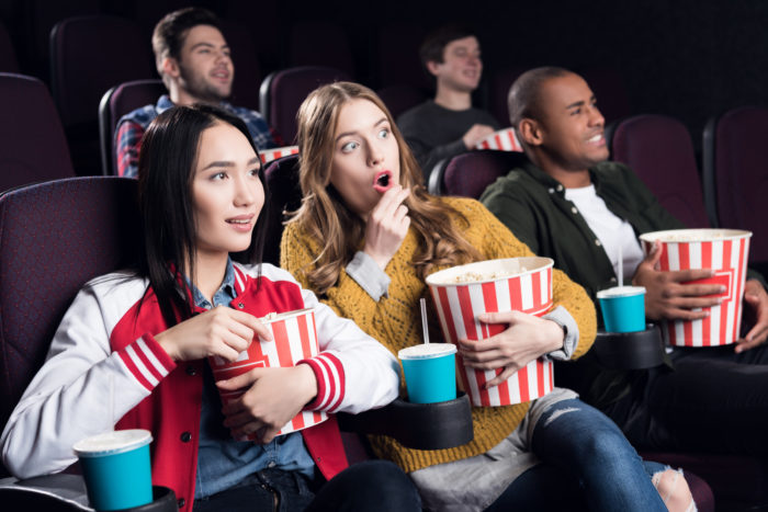 friends at a cinemark theater watching a movie and eating popcorn