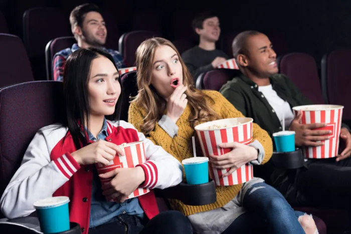 friends at a cinemark theater watching a movie and eating popcorn