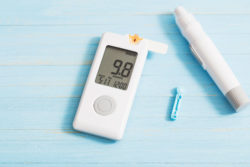 A glucometer and diabetes injection on blue table.