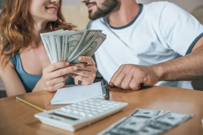 couple sitting at table holding settlement cash money
