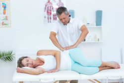 A masseur works on a woman's hip.