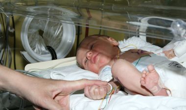 Infant in NICU with parent's hand