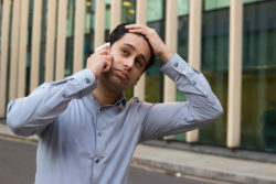 A man puts his hand on his head while taking a phone call.