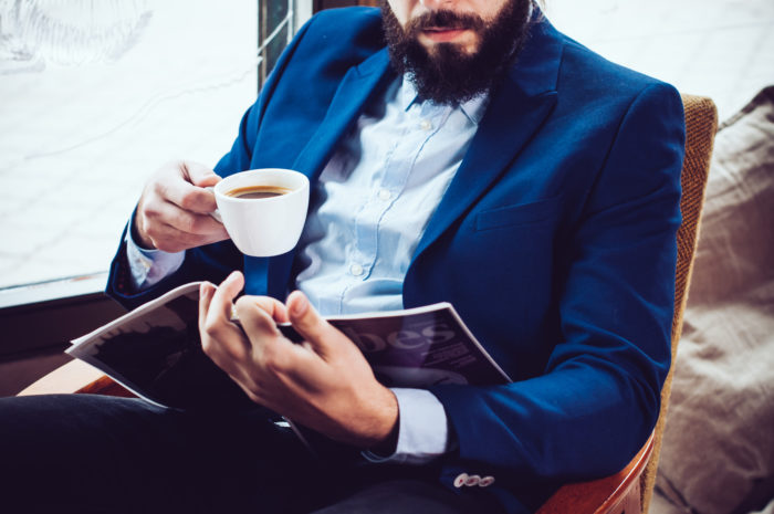 man reading playboy magazine while drinking coffee