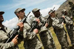 Members of the military stand with rifles.