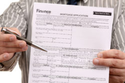A man holds out a mortgage application and a pen.